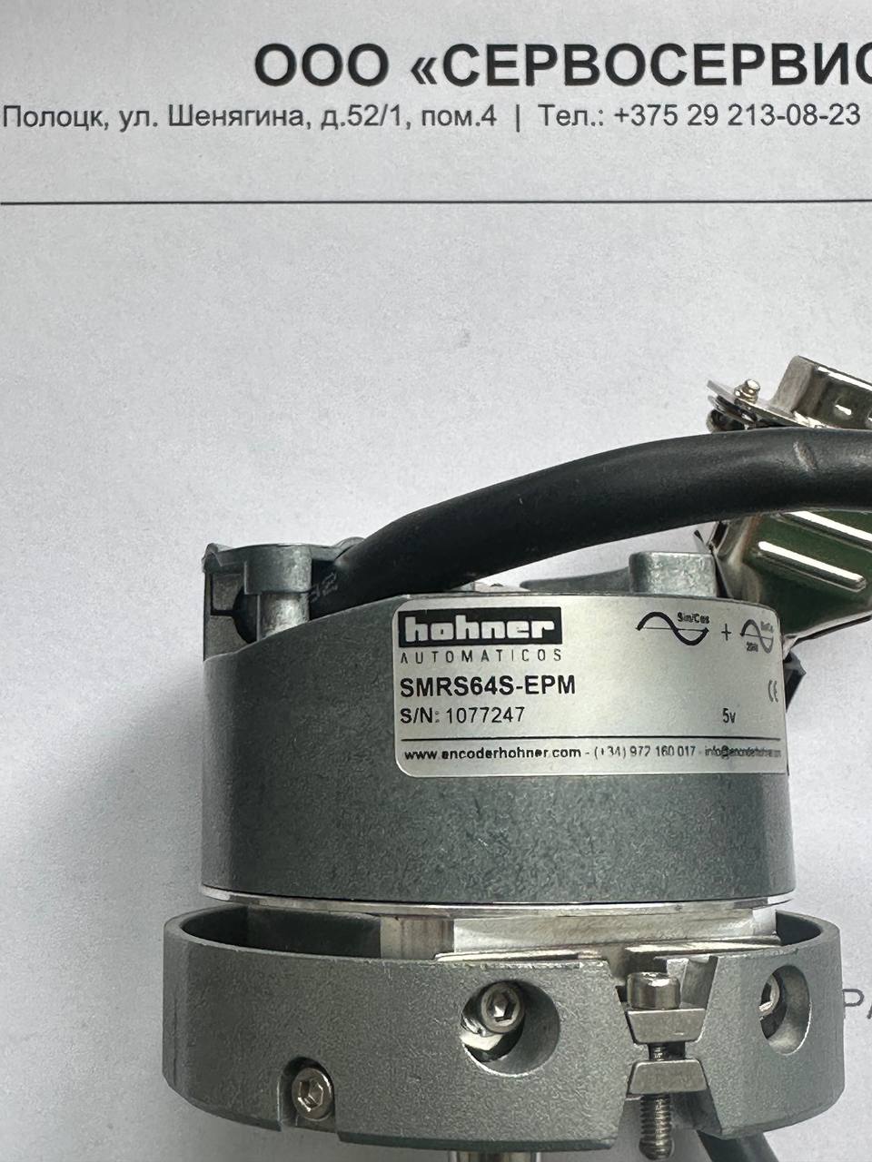 Крупный план корпуса промышленного энкодера Hohner SMRS64S-EPM с информационной табличкой и кабелем подключения в лаборатории сервисного центра перед началом ремонта.